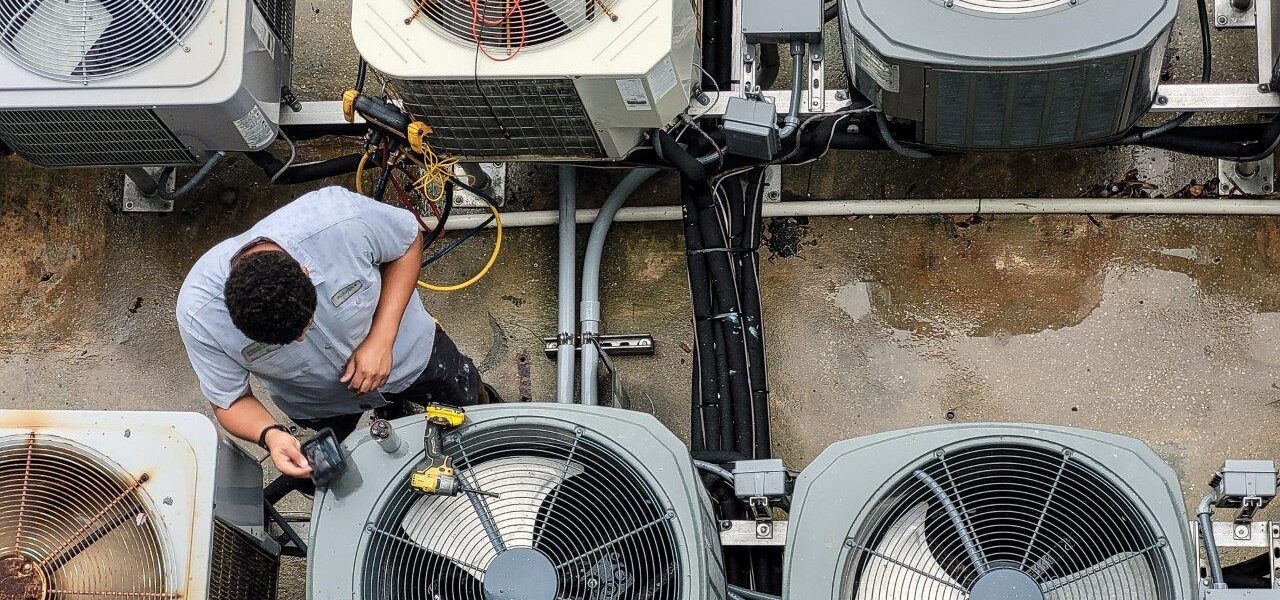 hvac technician inspecting A/C units apartment building