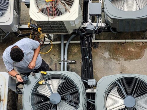 hvac technician inspecting A/C units apartment building