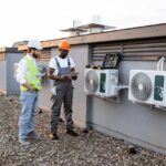 HVAC workers with tablet fixing rtu air conditioner on plant roof