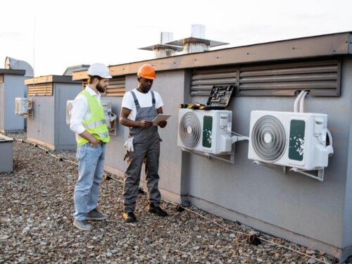 HVAC workers with tablet fixing rtu air conditioner on plant roof