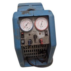 Blue portable pressure testing pump with two gauges and red/blue control valves, dusty and worn.