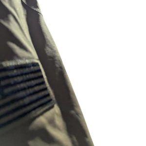 Close-up of a dark jacket sleeve with a ribbed, elastic panel and visible stitching on the left side of the frame.