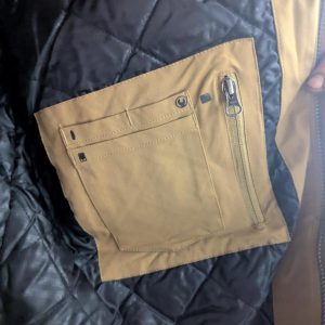 Tan fabric pocket panel with multiple card slots and a vertical zipper, sewn inside a dark quilted jacket.