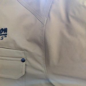 Beige outdoor jacket showing a front pocket with flap and prominent stitching seams.