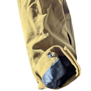 Close-up of a tan jacket sleeve with a blue inner lining peeking from the cuff.