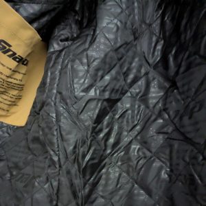 Close-up of black quilted jacket fabric with a yellow tag on the left edge.