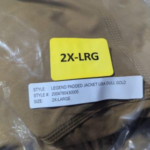 Yellow tag reading '2X-LRG' rests on a brown padded jacket; white label shows 'STYLE: LEGEND PADDED JACKET USA DULL GOLD' and 'SIZE: 2X-LARGE'
