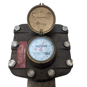 Old water meter with its cover open, showing the dial and an odometer reading about 5,757 gallons.