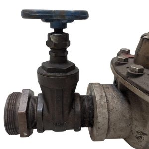 Neptune-3-FH-trident-turbine-awwa-class-II_9 | Chicago HVAC tools and supplies Close-up of an industrial valve with a blue T-handle on a metal pipe connection, showing threaded ends and a flanged joint