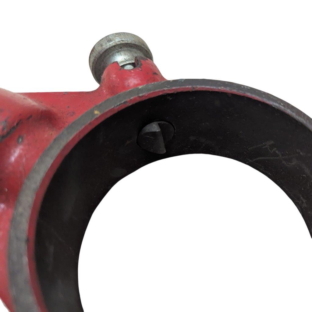 REED-R-12_8 | Chicago HVAC tools and supplies Close-up of a red metal pipe clamp with a circular black bore and a small screw visible inside the opening edge.