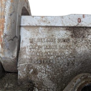 RIDGID-NO-378-Tube-Bender_4 | Chicago HVAC tools and supplies Close-up of a corroded metal mechanism with raised, weathered lettering reading: "TO RELEASE DRIVE ... LATCH HANDLES TOGETHER"; dusty, rusty edges indicate an old industrial part.