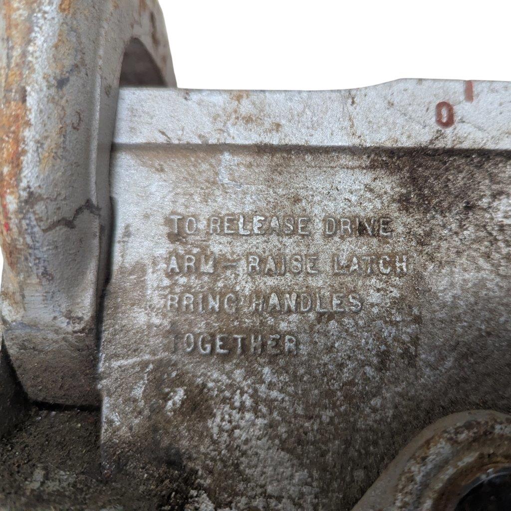 RIDGID-NO-378-Tube-Bender_4 | Chicago HVAC tools and supplies Close-up of a corroded metal mechanism with raised, weathered lettering reading: "TO RELEASE DRIVE ... LATCH HANDLES TOGETHER"; dusty, rusty edges indicate an old industrial part.