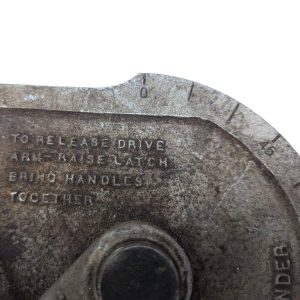 Ridgid-358-Model-Geared-Ratchet-Tube-Bender_11 | Chicago HVAC tools and supplies Close-up of a worn metal dial with engraved instructions reading 'TO RELEASE DRIVE ARMS LATCH BRING HANDLES TOGETHER' on a weathered surface around a circular edge.