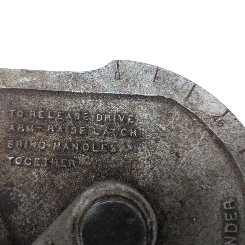 Ridgid-358-Model-Geared-Ratchet-Tube-Bender_11 | Chicago HVAC tools and supplies Close-up of a worn metal dial with engraved instructions reading 'TO RELEASE DRIVE ARMS LATCH BRING HANDLES TOGETHER' on a weathered surface around a circular edge.