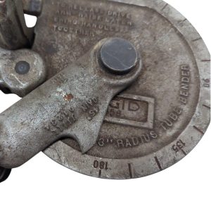 Ridgid-358-Model-Geared-Ratchet-Tube-Bender_12 | Chicago HVAC tools and supplies Rusty metal tool with a circular dial and a clamp, showing engraved numbers and a central screw.
