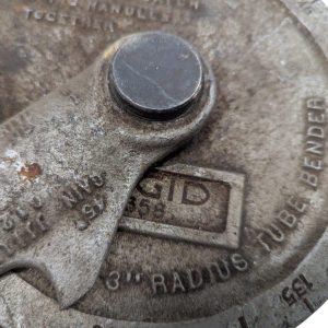 Ridgid-358-Model-Geared-Ratchet-Tube-Bender_9 | Chicago HVAC tools and supplies Close-up of a rusty industrial knob with a circular cap and a small window showing 'ID' on a textured metal surface.