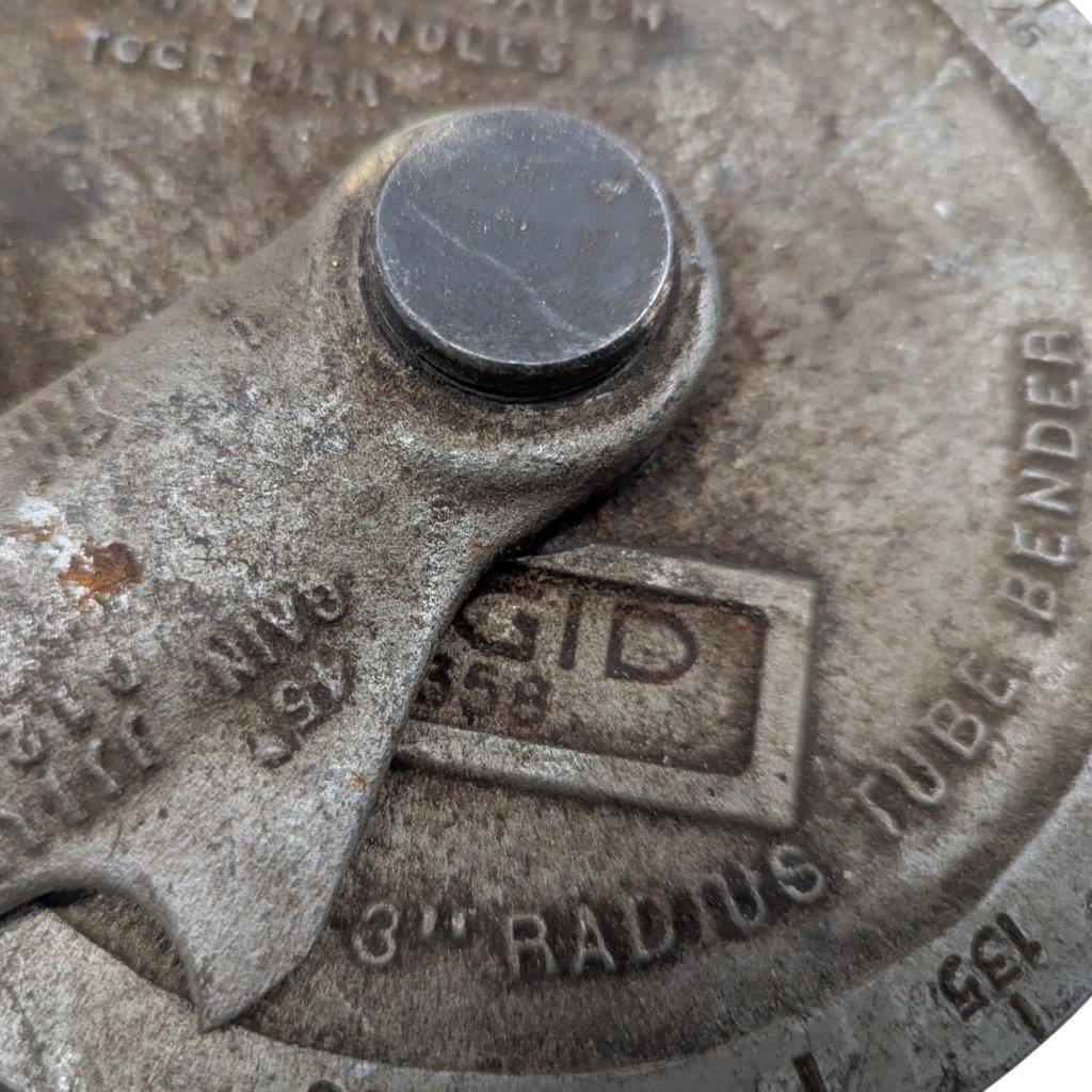 Ridgid-358-Model-Geared-Ratchet-Tube-Bender_9 | Chicago HVAC tools and supplies Close-up of a rusty industrial knob with a circular cap and a small window showing 'ID' on a textured metal surface.