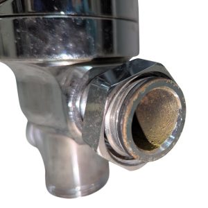 Close-up of a chrome plumbing valve with a rusted inner bore and exposed threading