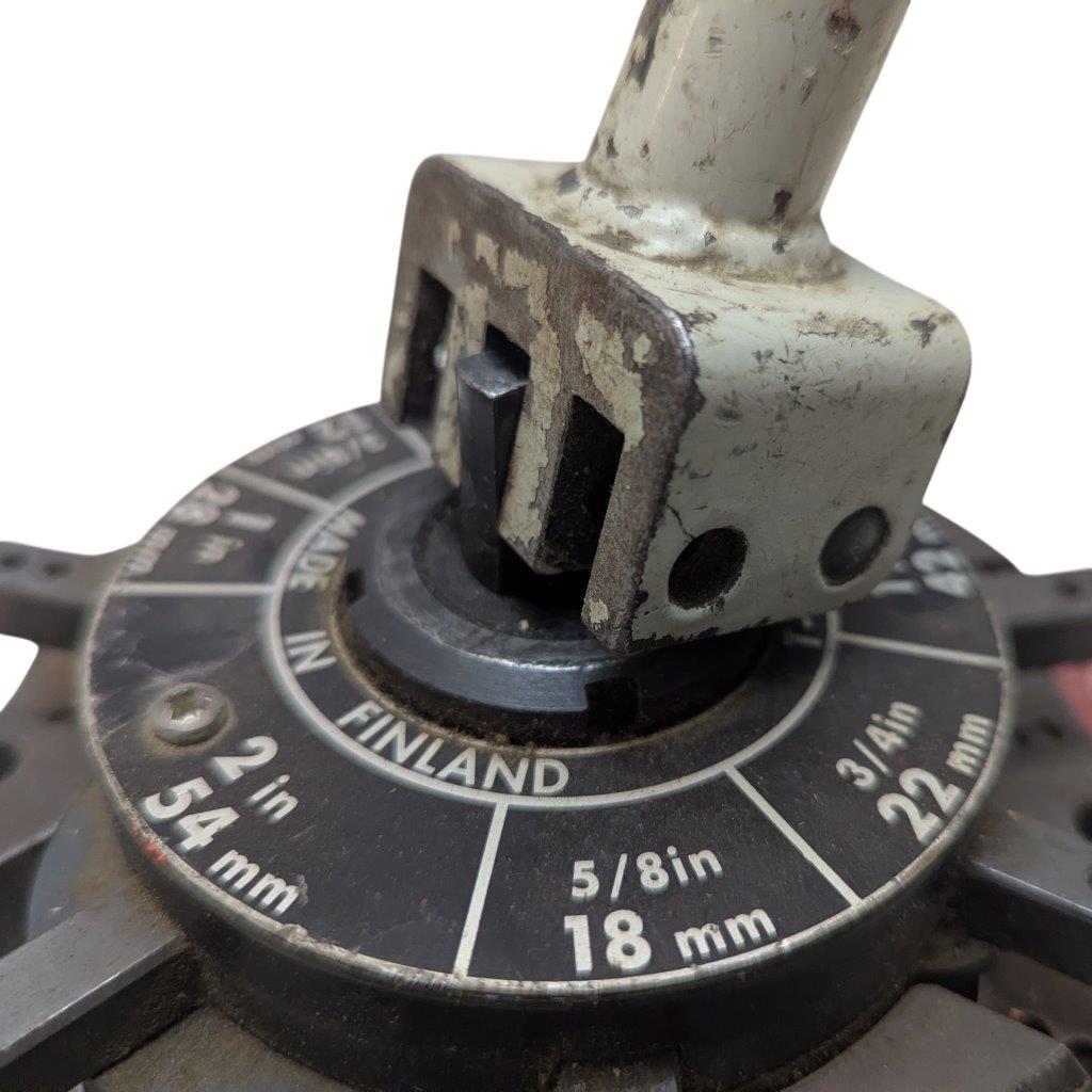 T-DRILL-ND-54-Tube-End-Notcher_13 | Chicago HVAC tools and supplies Close-up of a circular measurement dial with inches and millimeters, and a worn metal clamp resting on top, showing rust and grime.