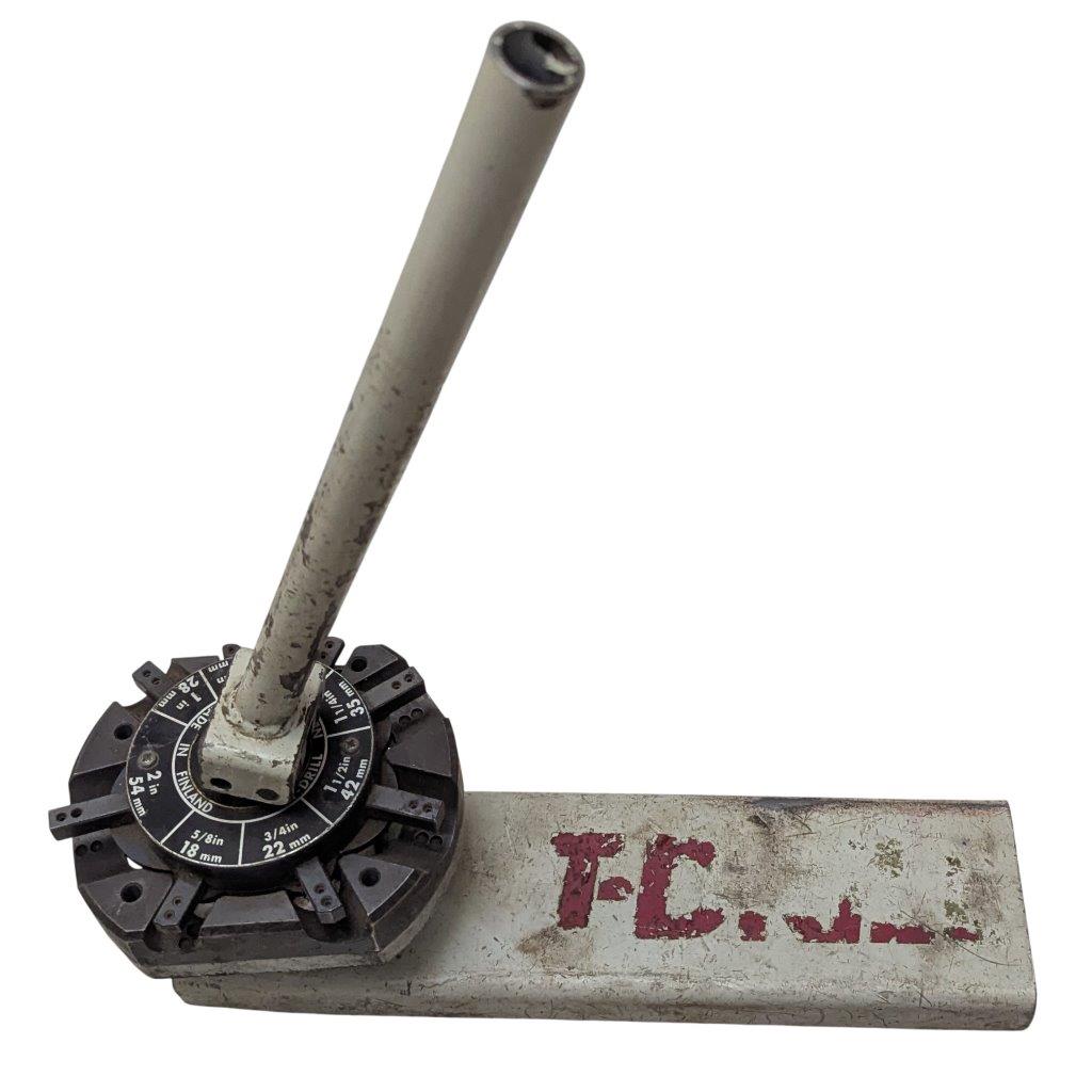 T-DRILL-ND-54-Tube-End-Notcher_2 | Chicago HVAC tools and supplies Manual metal pipe cutter with long handle and adjustable wheel, resting on a metal block marked with red letters.